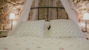 A bed with a canopy, floral bedding, and stone walls.
