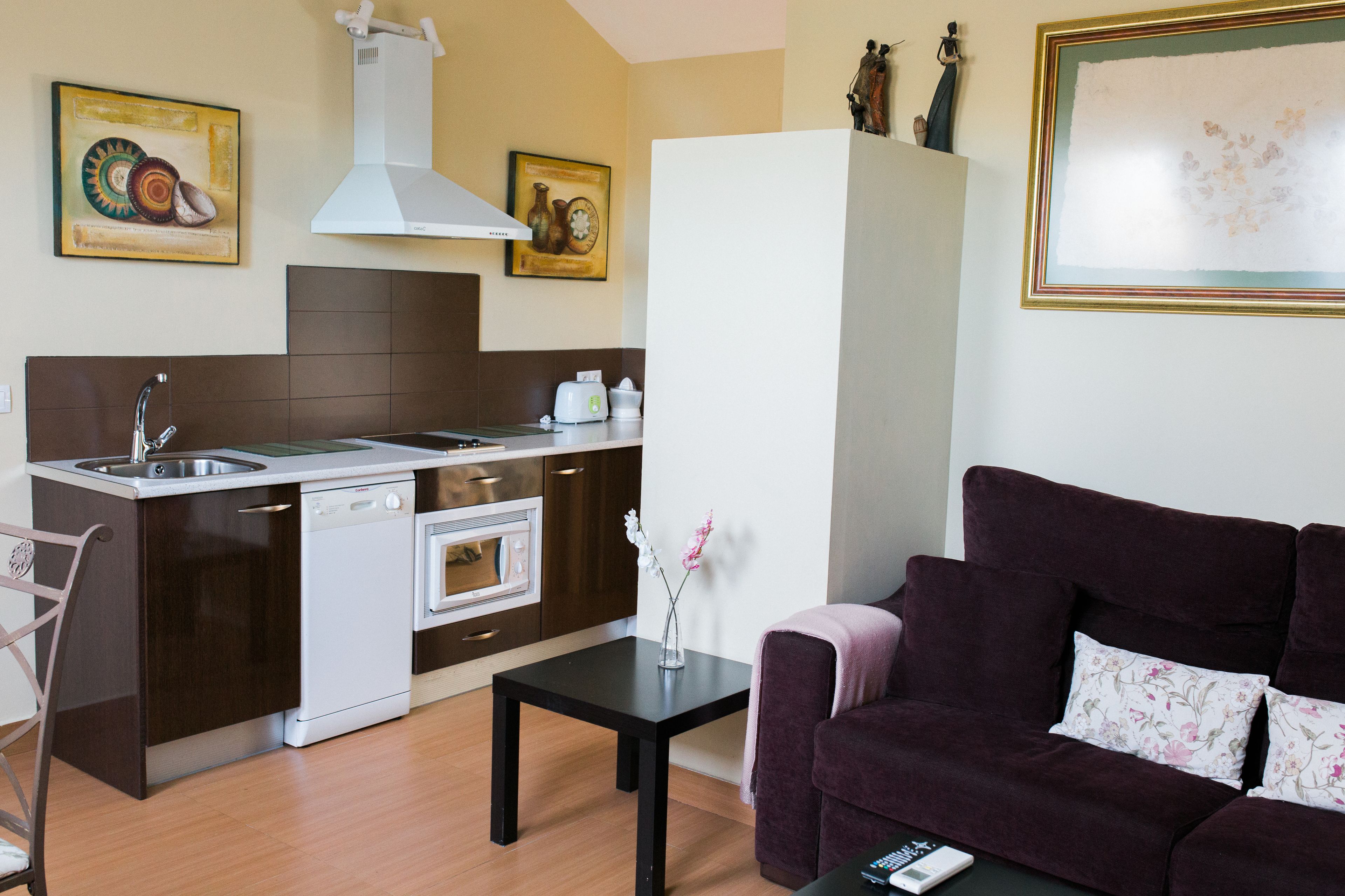 Una cocina compacta equipada con lavavajillas, horno y un comedor con mesa y sofá.