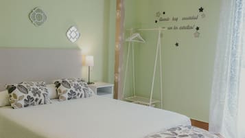 A neatly made bed with patterned pillows, a bedside table with a lamp, and a wall with decorative star and moon stickers.