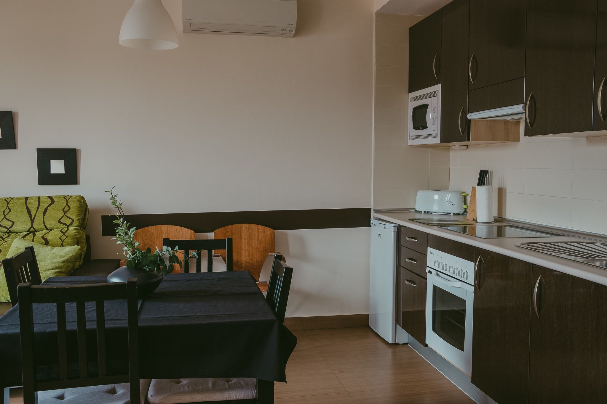 Una cucina compatta con zona pranzo, comprensiva di tavolo, sedie e forno a microonde.