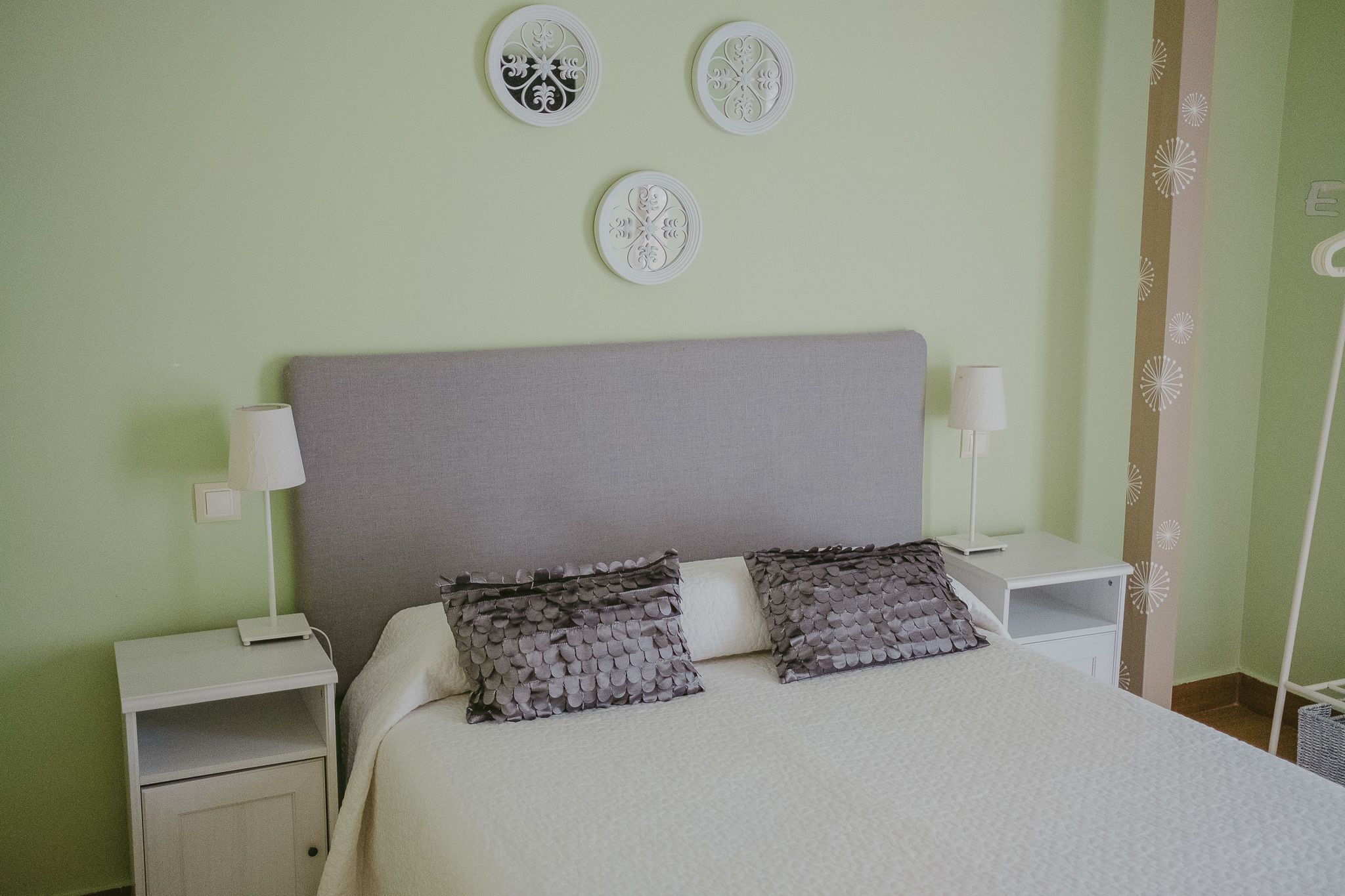 A bedroom with a bed, two nightstands, a lamp, and decorative wall art.