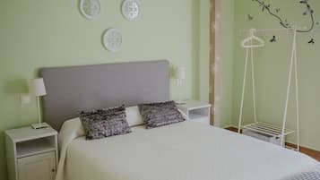 Una cama bien hecha con cabecera gris, dos mesitas de noche con lámparas y placas decorativas en la pared.
