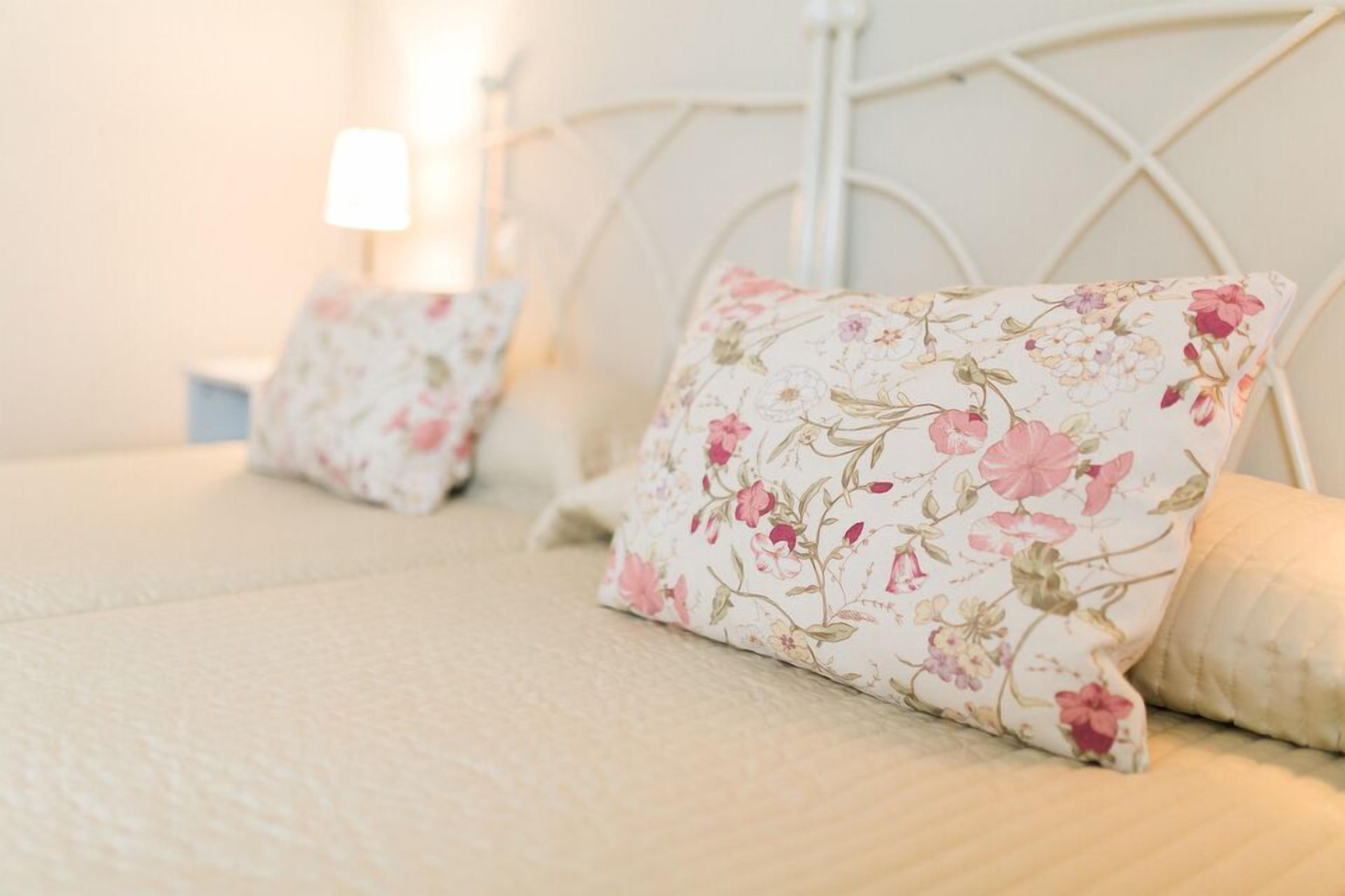 A bed with floral-patterned pillows and a white metal headboard.