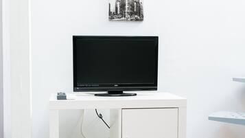 A white TV stand with a flat-screen TV, a small bowl, and a drawer.