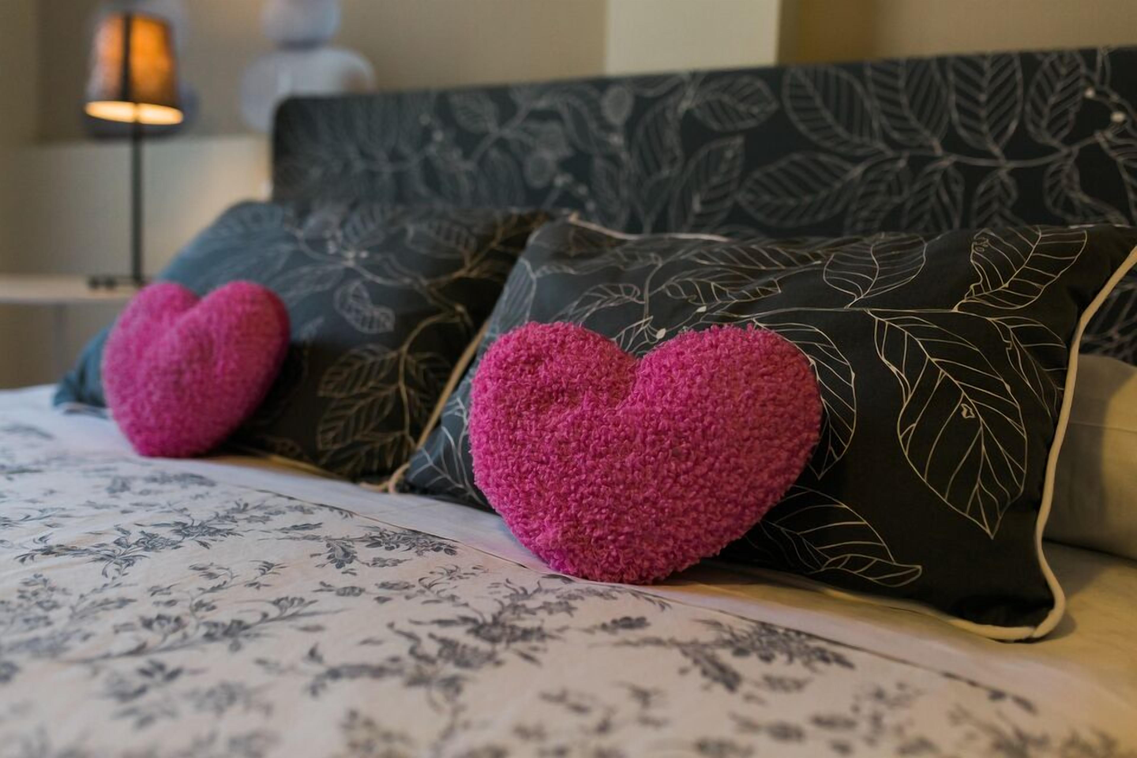 A bed with floral-patterned bedding and heart-shaped pillows.