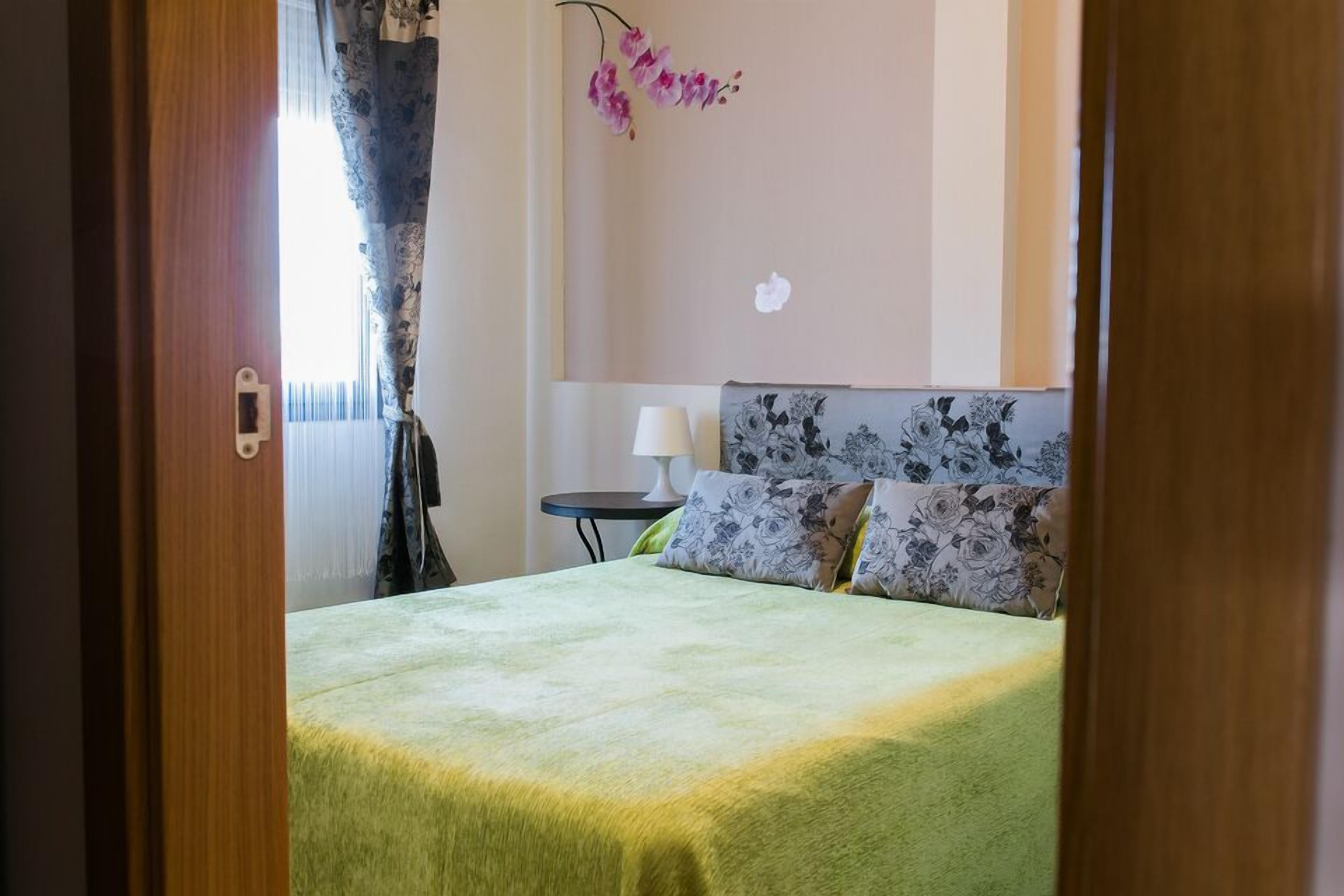 A hotel room with a bed, a nightstand, and a lamp.