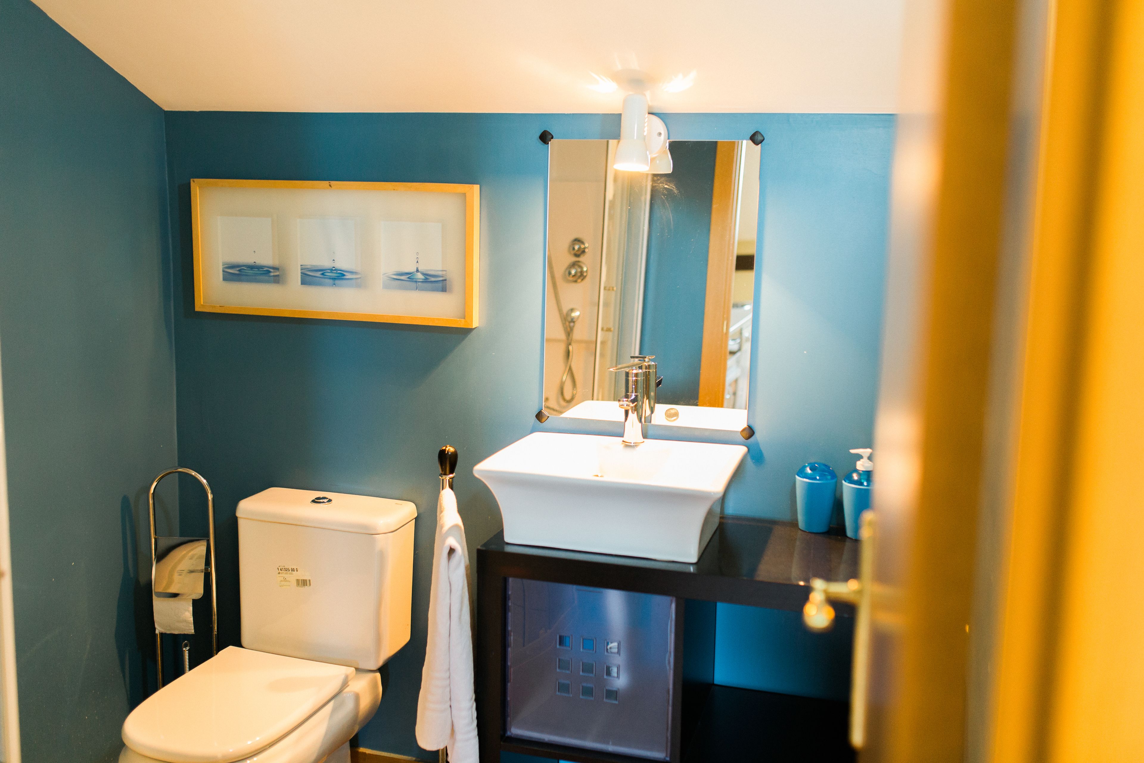A bathroom with a toilet, sink, and mirror.