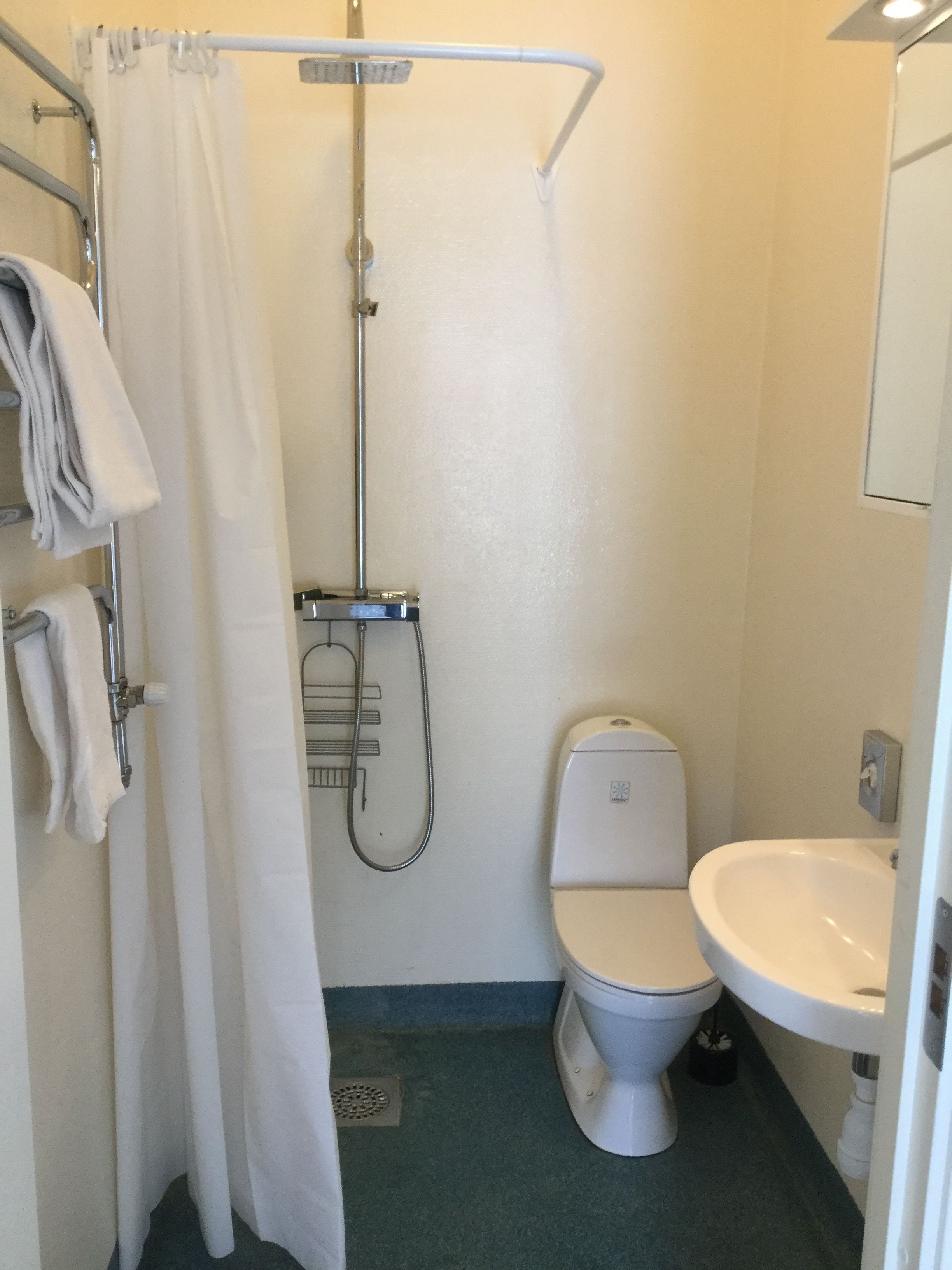 A small, compact bathroom with a shower, toilet, and sink.