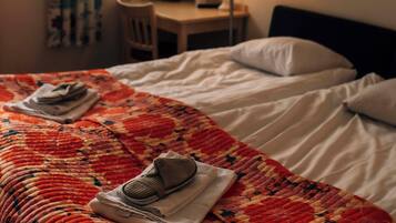 A hotel room with a bed, a chair, a desk, and a lamp.