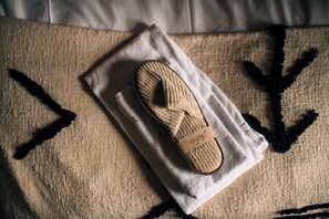 A pair of slippers on a towel, placed on a textured surface with a geometric pattern. - Wapnö Gårdshotell (Halmstad)