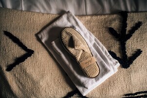 Un par de pantuflas sobre una toalla, sobre una superficie con diseño geométrico.