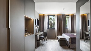 A modern hotel room with a bed, desk, chair, and a television.