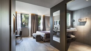 A modern hotel room with a bed, desk, chair, and a large mirror. - Hotel Upper Diagonal (Barcelona)
