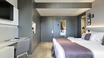 Une chambre d’hôtel moderne, dotée d’un grand lit, d’un bureau et d’une télévision.