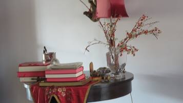 A table with books, a vase with branches, and a lamp.