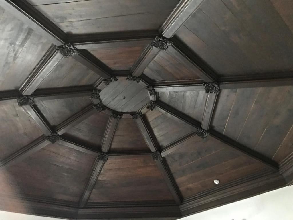Un sostre hexagonal amb panells de fusta fosca i motllures decoratives.