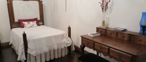 Une chambre à coucher bien rangée, avec un lit, une commode en bois et un petit banc.