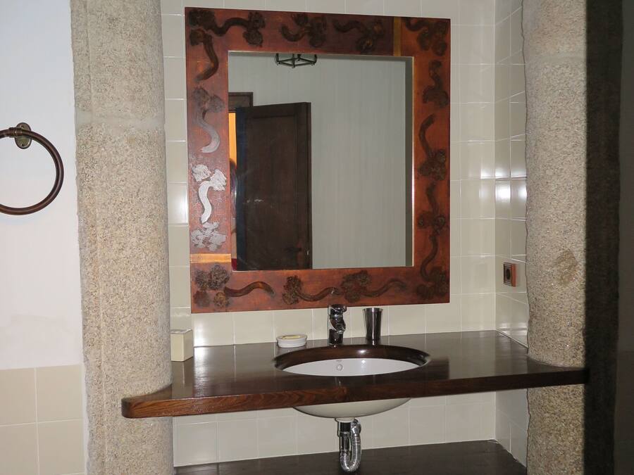 Une salle de bain avec un lavabo en pierre, un miroir doté d’un cadre décoratif et un porte-serviettes.