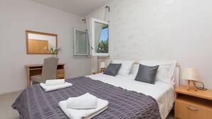 A bedroom with a bed, a desk, a chair, and a window with curtains. - Villa Carica (Omis)