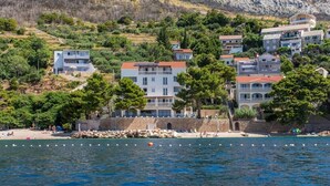 A coastal town with buildings along the shore, a sandy beach, and a clear view of the sea. - Villa Carica (Omis)