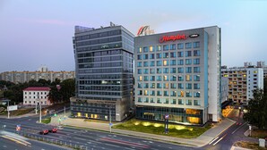 Een modern hotel met een opvallend 'Hampton by Hilton'-bord, omgeven door een verzorgde stedelijke omgeving.