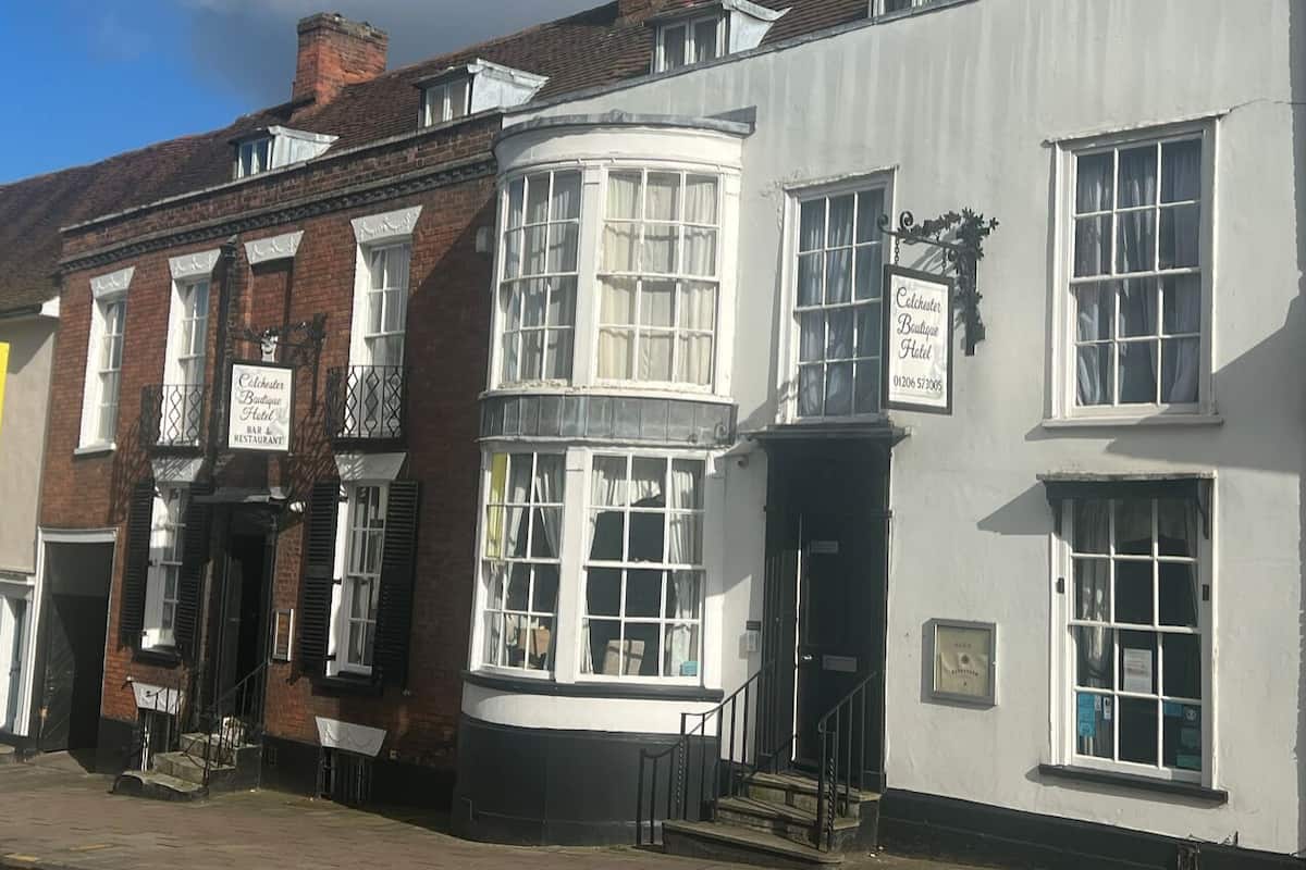 A traditional building with a corner window, a signboard for 'Caledonian Boutique Hotel', and a visible entrance with steps.