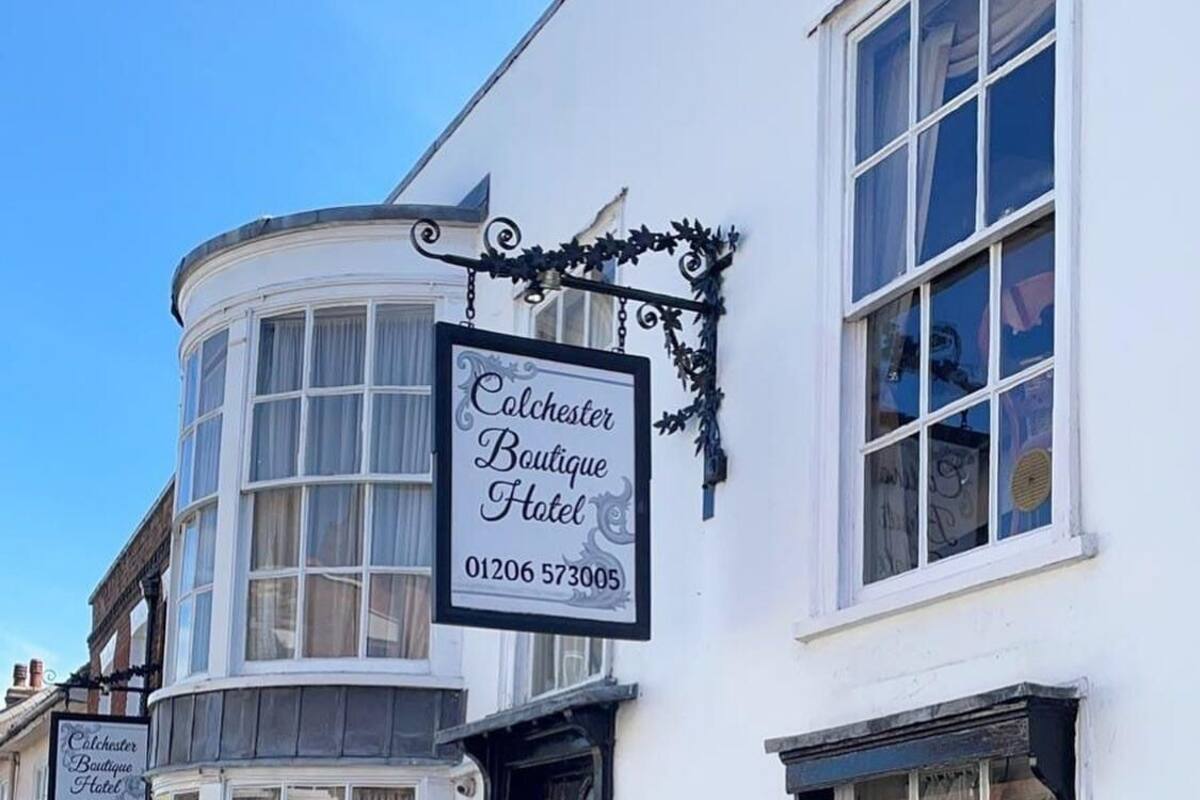 A white building with a sign for Colchester Boutique Hotel.