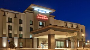 Un hôtel Hampton Inn & Suites au design moderne, doté d’une entrée imposante et d’une façade bien éclairée.