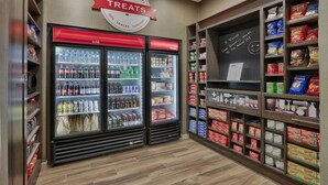 Une épicerie dotée de rayons réfrigérés étiquetés « froid » et « surgelé », et d’étagères remplies d’en-cas et de boissons.