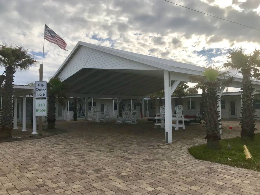 A covered outdoor seating area with chairs and tables, a sign for Ocean Café, and a sign for A1A Motel.