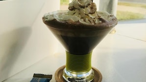A dessert in a glass bowl with whipped cream and chocolate pieces on a table near a window. - A1A Ocean Club (Flagler Beach)