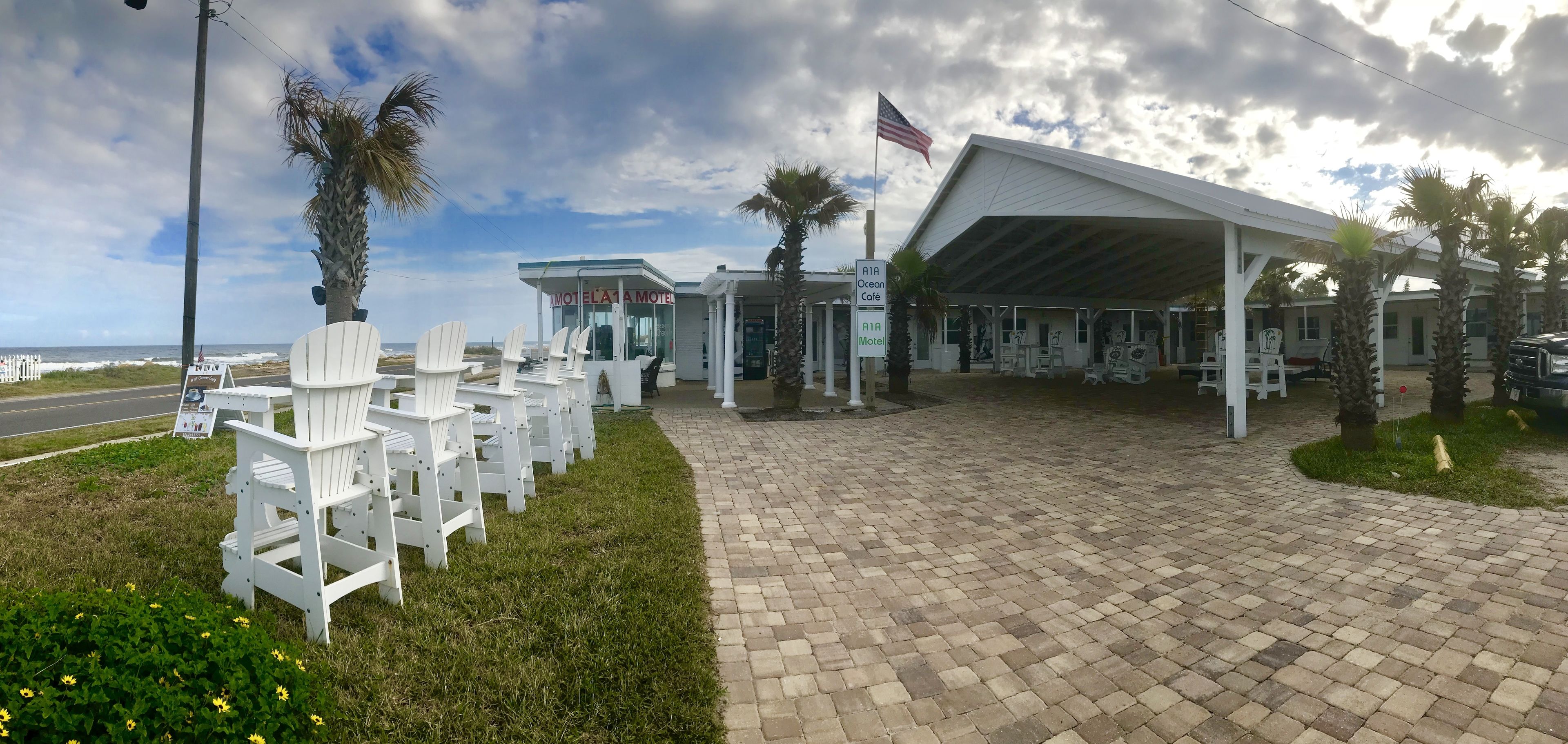 Un motel doté d’un espace extérieur aménagé avec une zone de repos couverte, d’une enseigne indiquant le « Ocean Cafe » et offrant une vue sur l’océan.