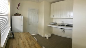 A compact kitchen with white cabinets, a wooden countertop, a sink, and a small step stool. - A1A Ocean Club (Flagler Beach)