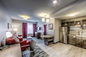 A modern hotel room with a kitchenette, a dining area with a table and chairs, and a seating area with a sofa and armchair. - Staybridge Suites Columbus Univ Area - OSU by IHG (Columbus)