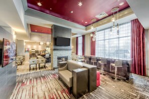 A modern hotel lobby with a fireplace, seating area, and a bar. - Staybridge Suites Columbus Univ Area - OSU by IHG (Columbus)