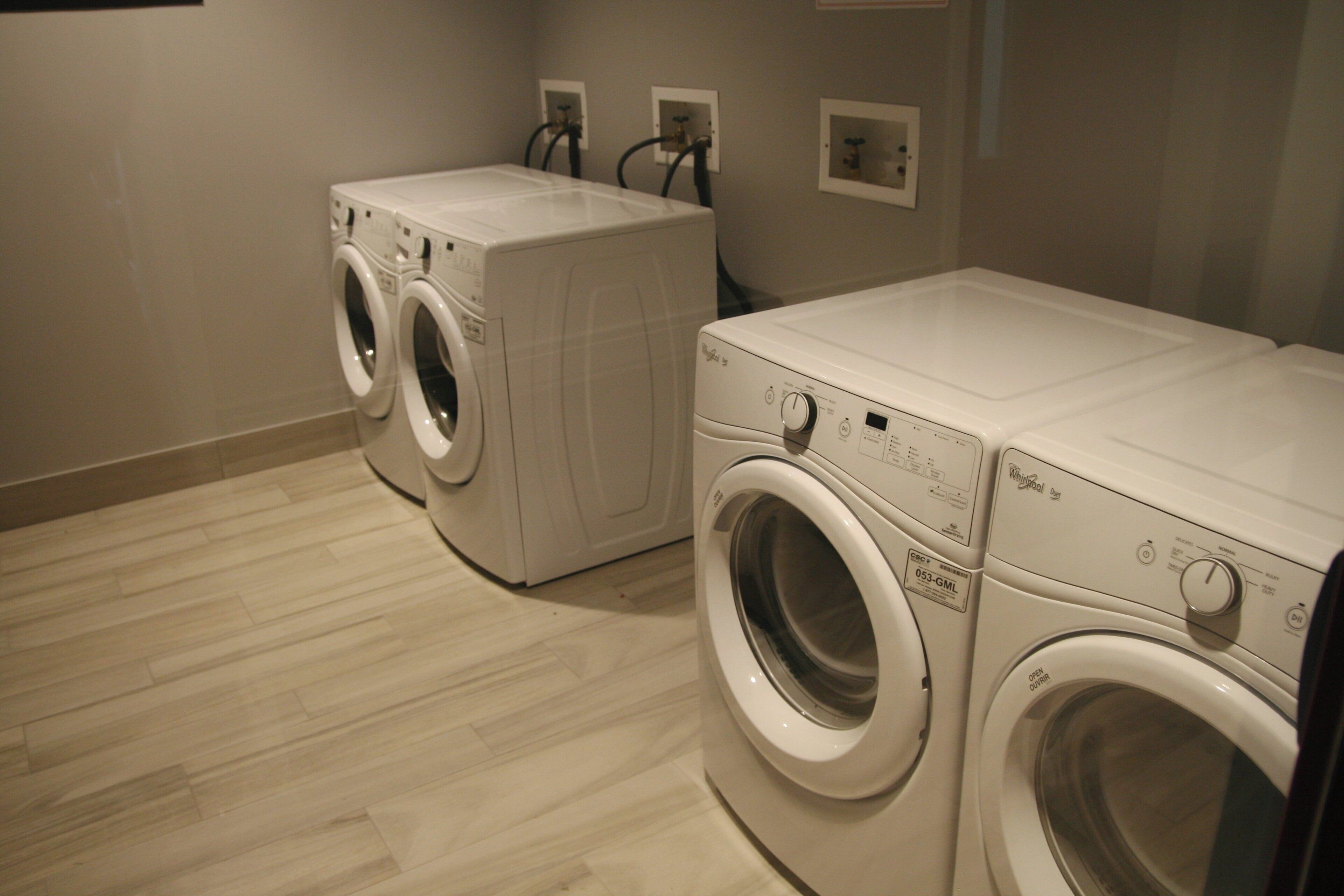 A laundry room with two front-loading washing machines and a dryer.