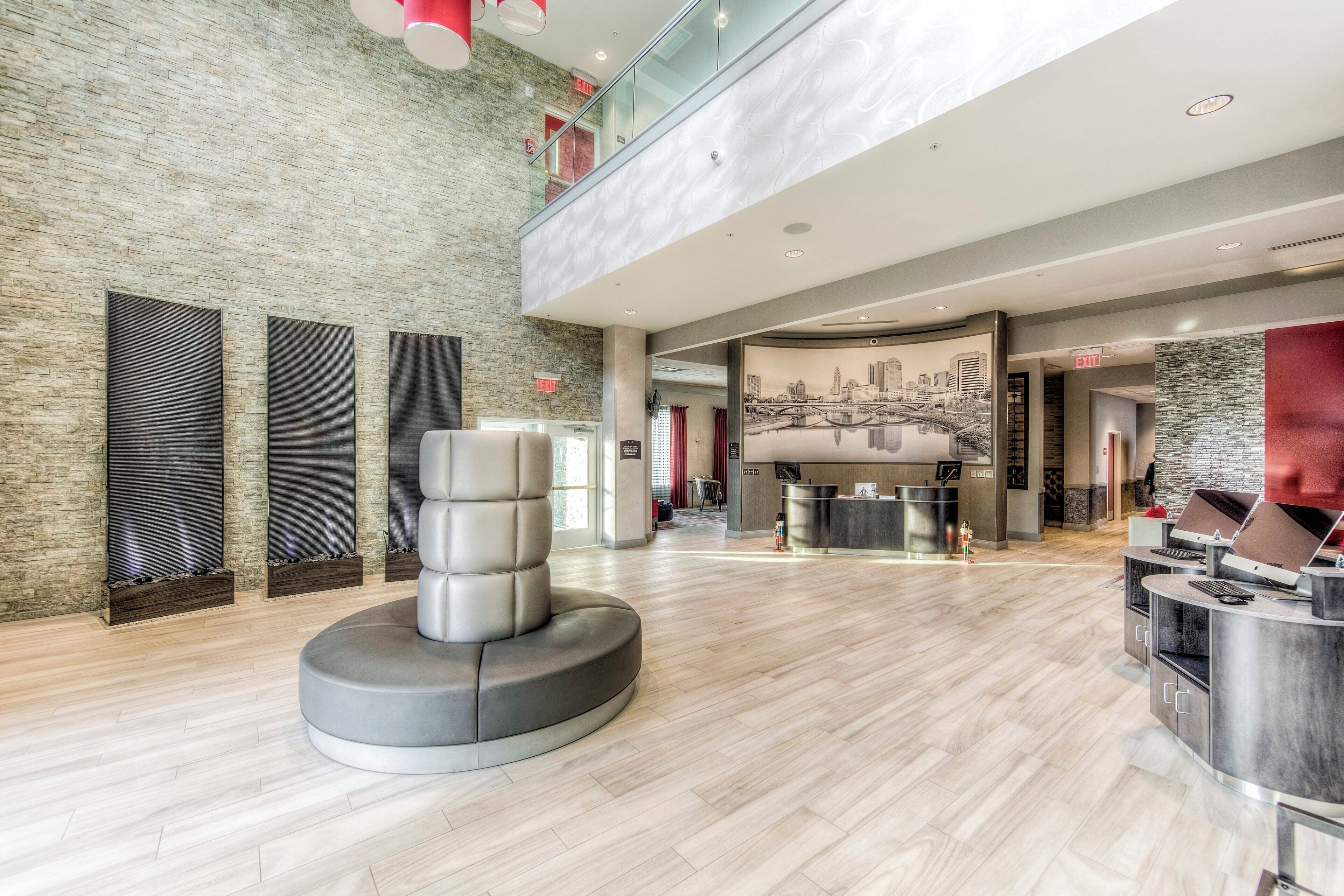 A modern lobby with a stone wall, a seating area, a reception desk, and a cityscape mural.