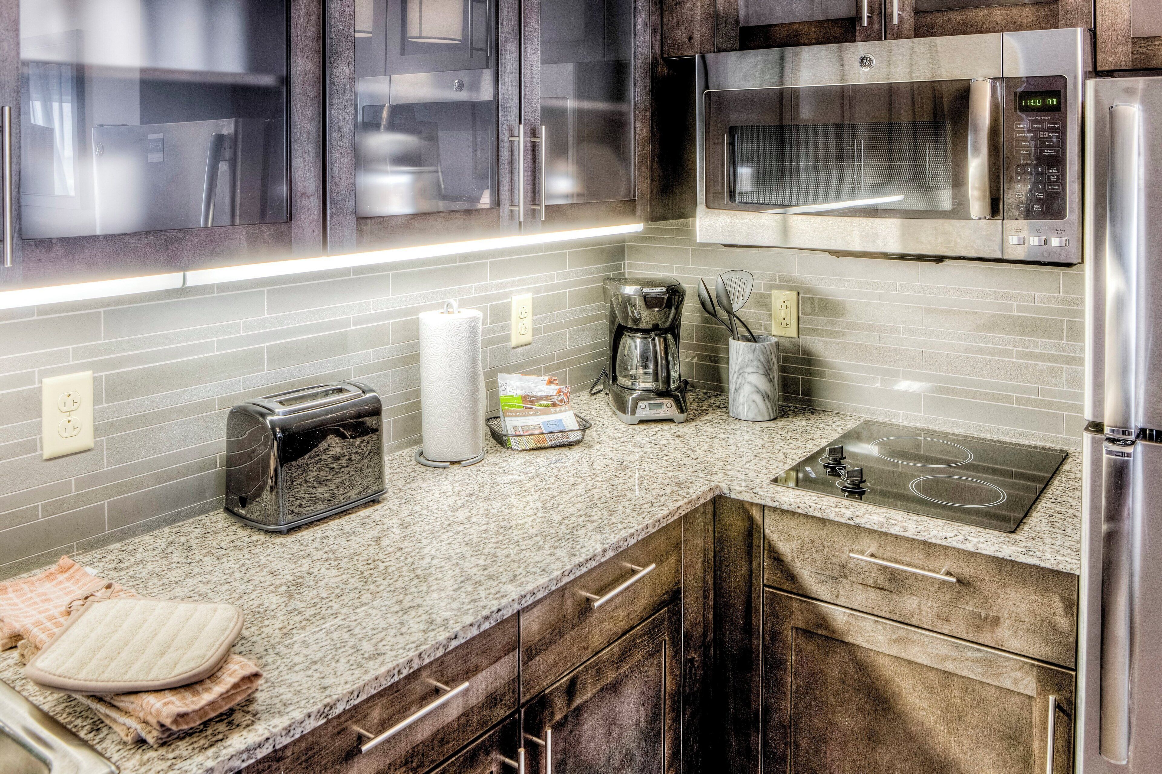 A modern kitchen with stainless steel appliances, a granite countertop, and wooden cabinets.