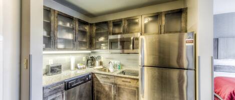 A compact kitchen with stainless steel appliances, a dishwasher, and a microwave.