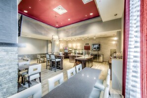 A modern kitchen with a central island, dining area with white chairs, and a red ceiling. - Staybridge Suites Columbus Univ Area - OSU by IHG (Columbus)