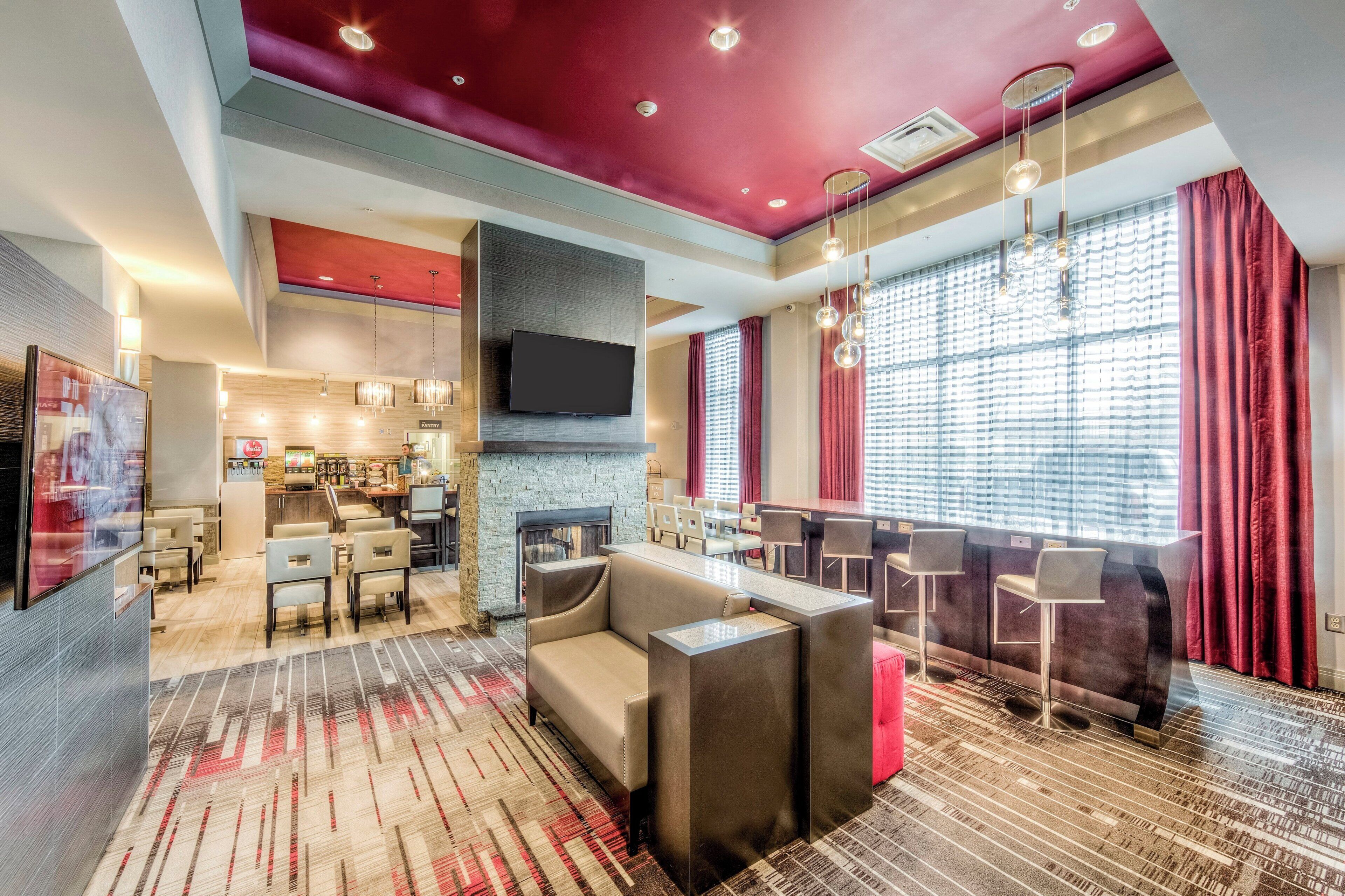 A hotel lobby with a seating area, a bar, and a television mounted on the wall.