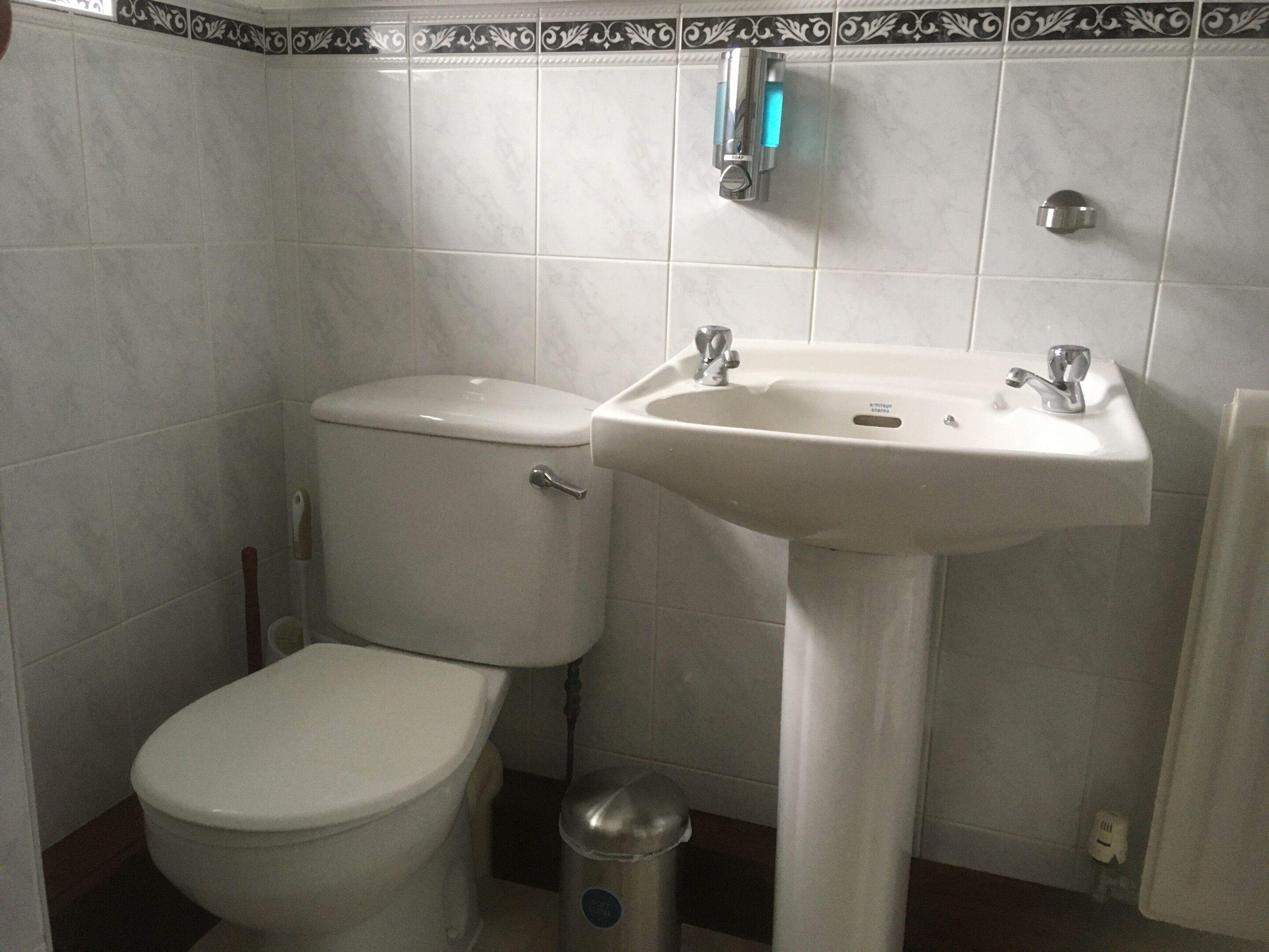 A bathroom with a toilet, sink, and a trash can.