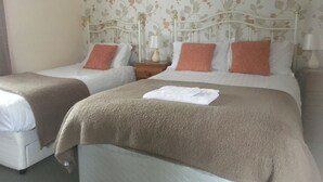 Une chambre d’hôtel avec deux lits, chacun recouvert d’une couverture blanche et marron, et agrémentée d’oreillers assortis.