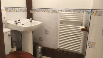 A bathroom with a white sink, toilet, and radiator.