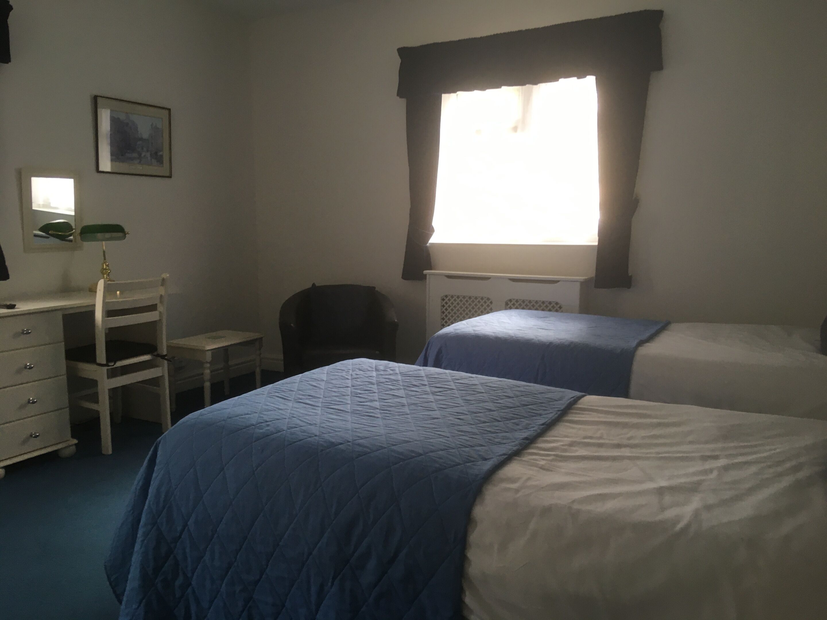 Un dormitorio con dos camas, un escritorio, una silla y una ventana.