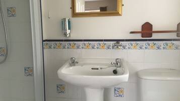Un baño con un lavabo blanco, un espejo y un inodoro.