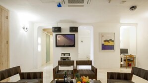 A modern living room with a flat-screen TV, two sofas, a coffee table with a fruit bowl and wine glasses, and a desk with a computer. - MS Hotel (Suwon)