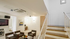 A modern living room with a flat-screen TV, seating area, and a staircase. - MS Hotel (Suwon)