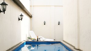 A swimming pool with a white chair and a bottle of wine, surrounded by white walls and a skylight. - MS Hotel (Suwon)