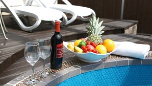 A poolside setting with a bottle of wine, two glasses, and a bowl of fruit. - MS Hotel (Suwon)